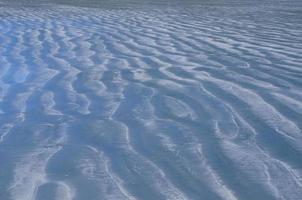 foto de fundo e textura de areia de cor azul que tem reflexo do céu azul.