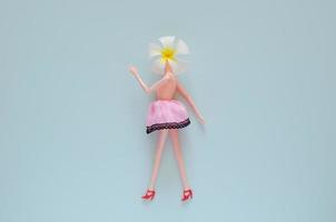 boneca feminina posando com flor de frangipani. conceito mínimo de beleza e moda. foto