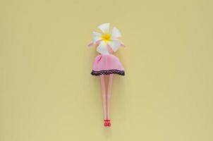 boneca feminina segurando flor de frangipani. conceito mínimo de beleza e moda. foto