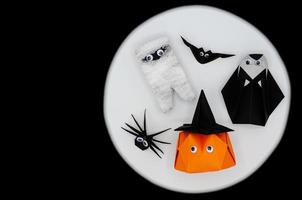 o origami de halloween ou dobradura de papel de abóbora jack o lanterna, múmia, freira, aranha e morcego em fundo branco e preto. foto