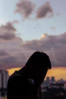 silhueta de homem deprimido chorando com fundo de céu e cidade de nuvens. foto