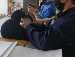 duas crianças usam telefones celulares jogam juntos tecnologia, sentados relaxam foto