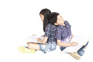 10 e 7 anos de escola asiática e menino sentado dormindo lendo livro juntos isolado sobre o branco foto