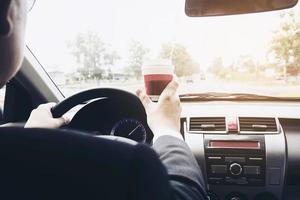 homem dirigindo carro segurando uma xícara de café foto