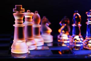 xadrez de vidro no tabuleiro de xadrez iluminado pela luz azul e laranja foto