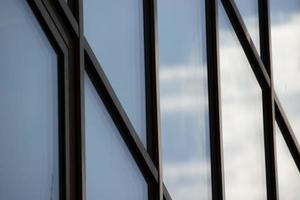 enormes janelas modernas com reflexão de céu azul e nuvens, foto horizontal. papel de parede, fachada de prédio de escritórios, painéis de vidro. geometria e perspectiva