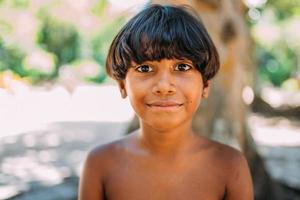 jovem índio da tribo pataxo do sul da bahia. criança indiana sorrindo e olhando para a câmera. foco no rosto foto