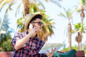 jovem viajante masculino falando no celular e segurando o mapa