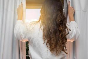 pessoas e conceito de esperança - close-up de mulher feliz abrindo cortinas de janela foto