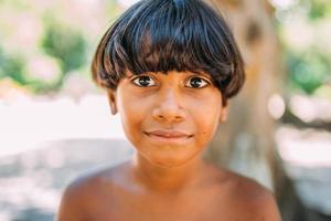 jovem índio da tribo pataxo do sul da bahia. criança indiana sorrindo e olhando para a câmera. foco no rosto foto