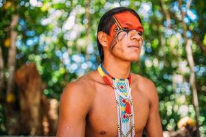 índio da tribo pataxo sorrindo. índio brasileiro do sul da bahia com colar e pinturas faciais tradicionais olhando para a direita foto