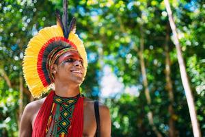 índio da tribo pataxo com cocar de penas olhando para a direita. indígenas do brasil com pinturas faciais tradicionais. foto