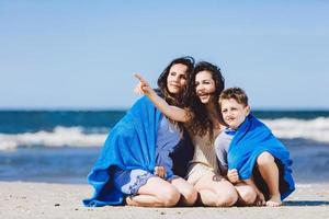 família sentada na praia, irmã mais velha apontando o dedo foto