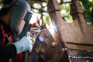 soldador especialista em estrutura de construção de solda, faísca de soldagem, soldador está soldando fabricação de metalurgia e serviço de manutenção de construção. foto