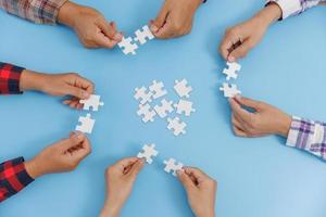 o conceito de cooperação. um grupo de empresários montando quebra-cabeça. trabalho em equipe, ajuda e apoio nos negócios. foto