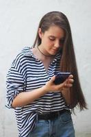 uma jovem está olhando para uma mensagem em seu telefone, uma adolescente está enviando mensagens de texto nas redes sociais foto