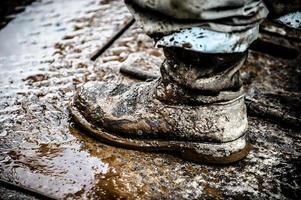 botas enlameadas de trabalhador de plataforma de petróleo foto