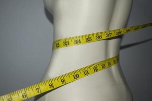 close-up de fita métrica na cintura fina do manequim foto