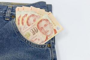 fechar dólares de singapura em um bolso de jeans em fundo branco foto