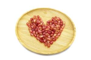 forma de coração de romã fresca na placa de madeira isolada no fundo branco foto