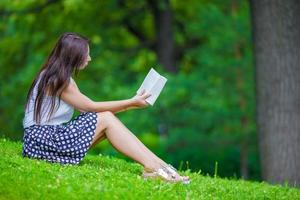 menina lendo um livro lá fora no parque