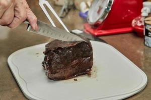 chef corta pedaço de carne frita com cebola em molho de vinho em fatias para servir. cozinha gourmet francesa foto