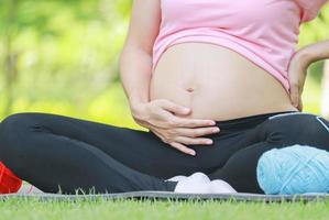 mulher grávida asiática sente-se e relaxe no parque. conceito de relaxamento de uma mulher grávida. foto