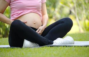 mulher grávida asiática sente-se e relaxe no parque. conceito de relaxamento de uma mulher grávida. foto