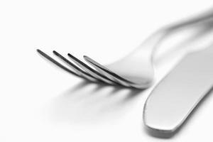 o garfo e a faca brilhantes de metal em um fundo branco. foto