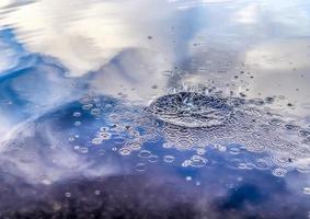 bela água em um lago com salpicos de água e ondulações na superfície com nuvens e reflexos do céu azul foto