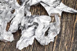 pedaços amassados de papel alumínio de chocolate em uma mesa de madeira foto