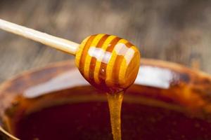 uma colher de mel juntamente com mel de abelha de alta qualidade foto