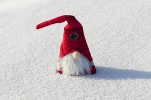 um anão com um chapéu vermelho na neve foto