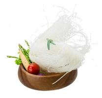 macarrão de arroz cru em uma tigela no fundo branco foto