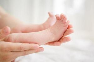 pernas de bebê nas mãos da mãe