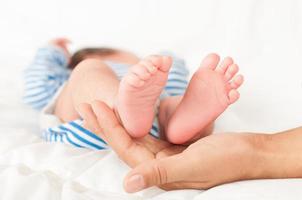 mãos da mãe segurar as pernas do bebê foto