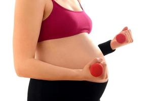 mulher esperando um bebê treinando com halteres rosa