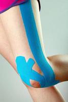 perna com fita azul de fisioterapia foto