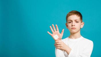 menino infeliz com gesso adesivo branco na mão foto