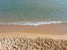 pequenas ondas quebrando na areia clara da praia foto
