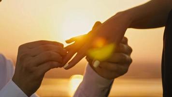 anel de casamento colocado no dedo mãos tocando pôr do sol noiva noivo homem mulher proposta de casamento férias lua de mel, horizontal foto