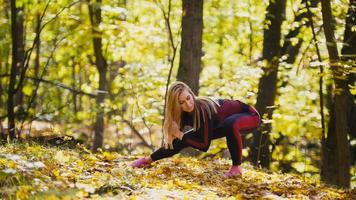 mulher fazendo exercícios de fitness ao ar livre. feminino alongamento na floresta de outono. garota magra no treino - agachamento foto