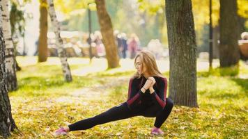 sexy atraente modelo de biquíni-fitness loira feminina que se estende no parque outono no chão coberto de folhas amarelas - flexibilidade de pernas - o lado direito foto