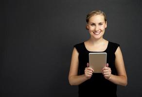 jovem mulher usando um tablet sobre fundo escuro foto