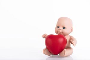 boneca, baby, com um coração vermelho nas mãos. conceito de proteção infantil. foto