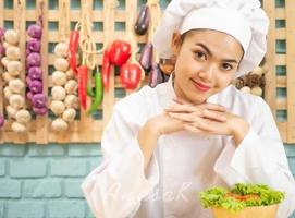 mulher asiática em uniforme de chef está cozinhando na cozinha foto