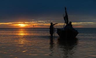 pescador de silhueta no barco na praia. foto