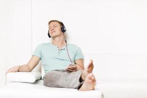 homem relaxado ouvindo música com fones de ouvido e olhos fechados.