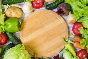 placa de corte do círculo e legumes em fundo branco de madeira. Alimentação saudável
