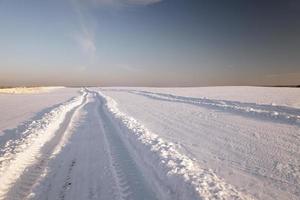 a estrada para um campo - a estrada rural em um campo agrícola em uma temporada de inverno foto